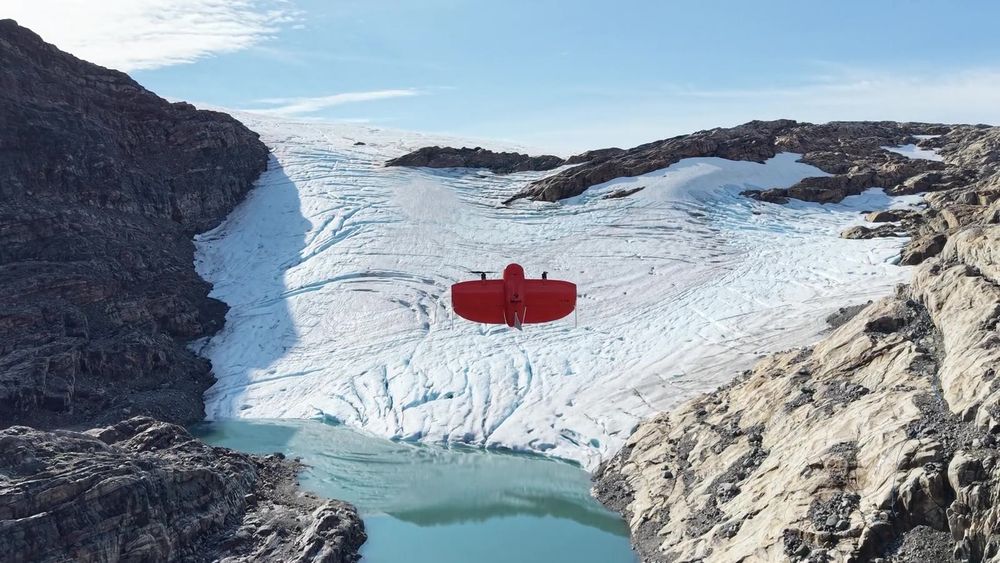 A fixed-wing drone flying over a snow-covered glacier above a meltwater lake on Folgefonna